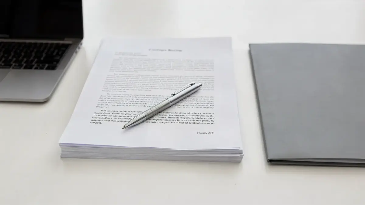 Vertrag mit Geheimhaltungsklausel auf Schreibtisch neben Stift und Laptop