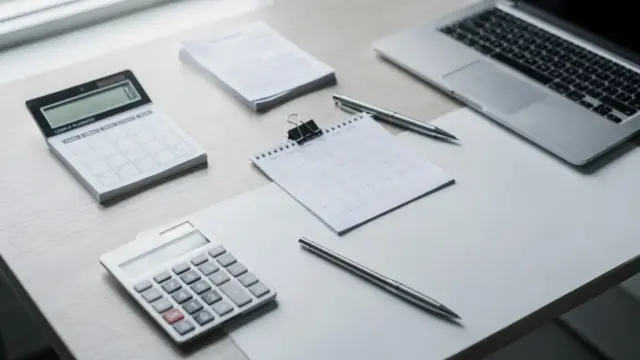 Büro-Desk mit Kalender, Taschenrechner und Unterlagen zur Laufzeit von Unternehmenskredit